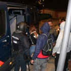 Pla general de la noia detinguda pujant a la furgoneta de la Policia Nacional, envoltada d'agents.
