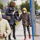 Una chica con máscara andando con su madre por la calle.