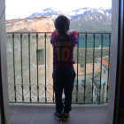 Un nen observant des del balcó de casa l'entorn natural del seu municipi, durant el confinament.
