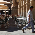 Un home amb mascareta passa davant d'una terrassa d'un restaurant de la plaça Major de Salamanca.