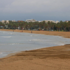 La platja de Llevant de Salou amb només algunes persones passejant vora el mar.