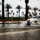 Un coche circulando por el paseo inundado.