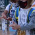 Dos alumnos de primaria lavándose las manos con gel hidroalcohólico en el acceso de la escuela Sant Llàtzer de Tortosa.