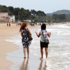 Dues dones d'esquenes caminant a la platja Llarga de Tarragona en l'últim dia de la fase 1.