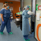 Una profesional sanitaria entra en una habitación ocupada por un positivo por coronavirus en el Hospital Clínic.