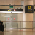 Una pasajera esperando delante la zona de llegadas en el aeropuerto de Barcelona.