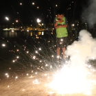 Un petardo explotando y un niño en segundo plano asustado en el paseo de Roses.