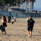 Una chica abandona la playa de la Nova Icària, al lado de un agente policial, poco antes de que cerrara al público para esta Noche de Sant Joan.