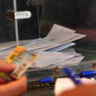 Foto de archivo de una urna y una mano que comprueba el DNI para poder votar.
