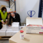 Vacunas en primer plano y operarios apilando cajas de vacunas de AstraZeneca en Cataluña.