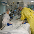 Dos sanitaris visitant un pacient de covid a l'UCI de l'Hospital Clínic protegits amb EPI.