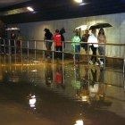 Un grup de persones passa per un pont del barri del Serrallo inundat per la pluja.
