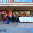 Dos mujeres entran en un supermercado Spar en Reus, mientras una veintena de trabajadores protestan.