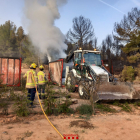 Els bombers treballen amb una retroexcavadora per treure runa que fumejava en un contenidor.