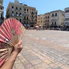 Una persona abanicant-se ahir a la plaça del Mercadal de Reus.
