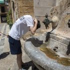 Un jove es refresca en una de les fonts de les escales de la catedral de Tarragona buscant alleujar les altes temperatures.