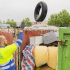 Un treballador de Reus Net dipositant escombraries en un contenidor ple de deixalles abandonades a la via pública.