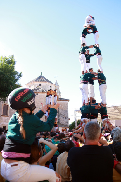 Una jove castellera aplaudeix mentre els Castellers de Caldes carreguen i descarreguen un 3 de 7 amb l'agulla